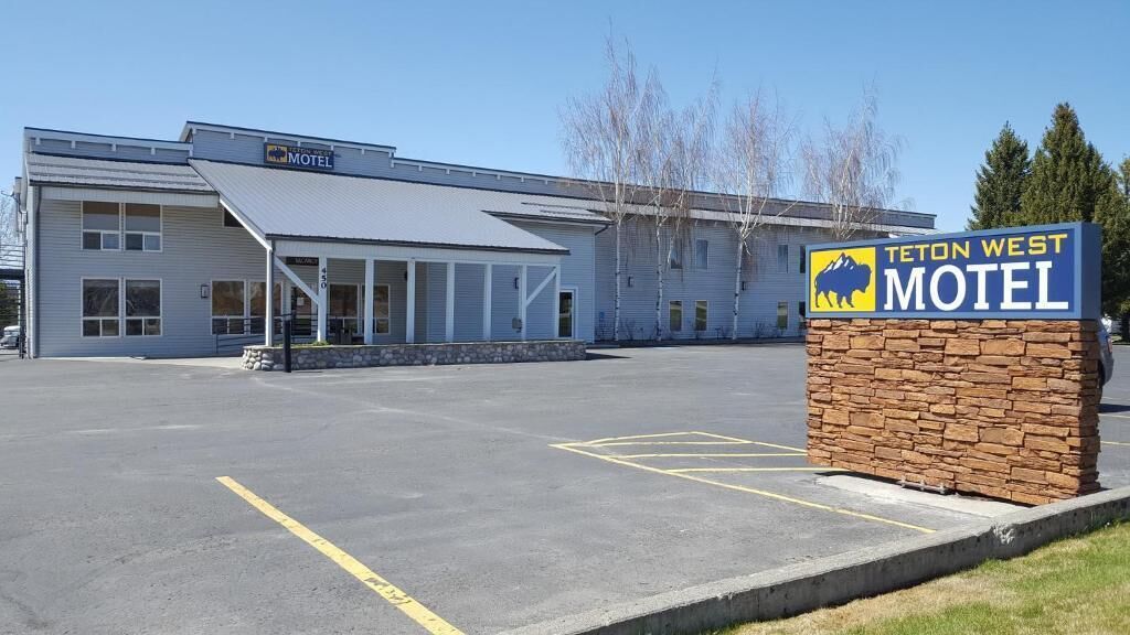 A Teton West Motel with a large parking lot and a covered outdoor area.