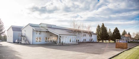 A motel with a parking lot, a covered area, and a signboard.