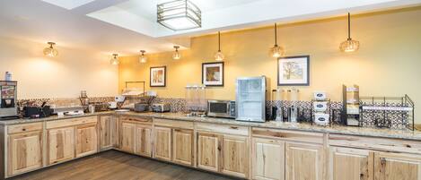 A kitchen with wooden cabinets, a countertop with appliances, and pendant lighting.