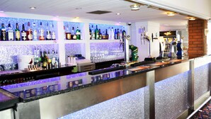 A bar area with shelves of liquor bottles, a cash register, and a beer tap. - Lyndene Hotel (Blackpool)