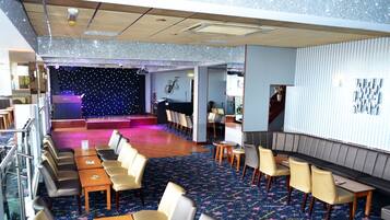 A hotel lobby with a stage, seating areas, and a star-patterned carpet.