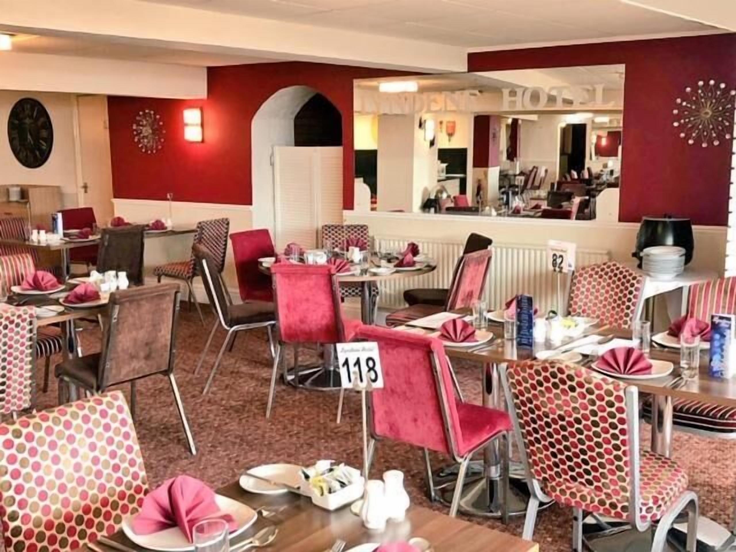 A hotel dining area with red and white decor, multiple tables, and chairs.