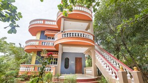 A multi-level building with a central staircase, surrounded by lush greenery. - GuestHouser 3 BHK Cottage 26O3 (Vanur)