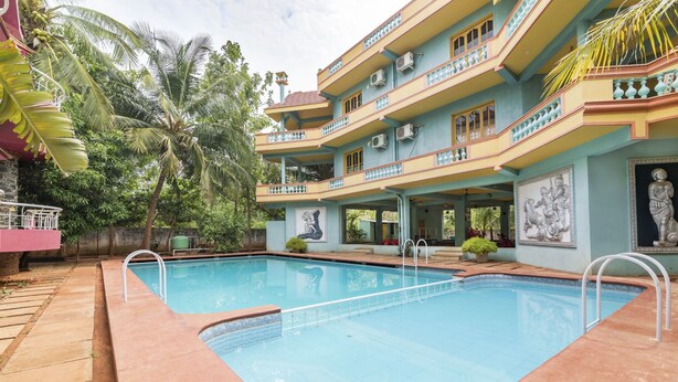A swimming pool with a tiled deck, surrounded by a multi-story building with balconies and air conditioning units. - GuestHouser 3 BHK Cottage 26O3 (Vanur)