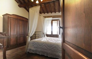 Un dormitorio con cama de madera, dosel y un amplio armario.