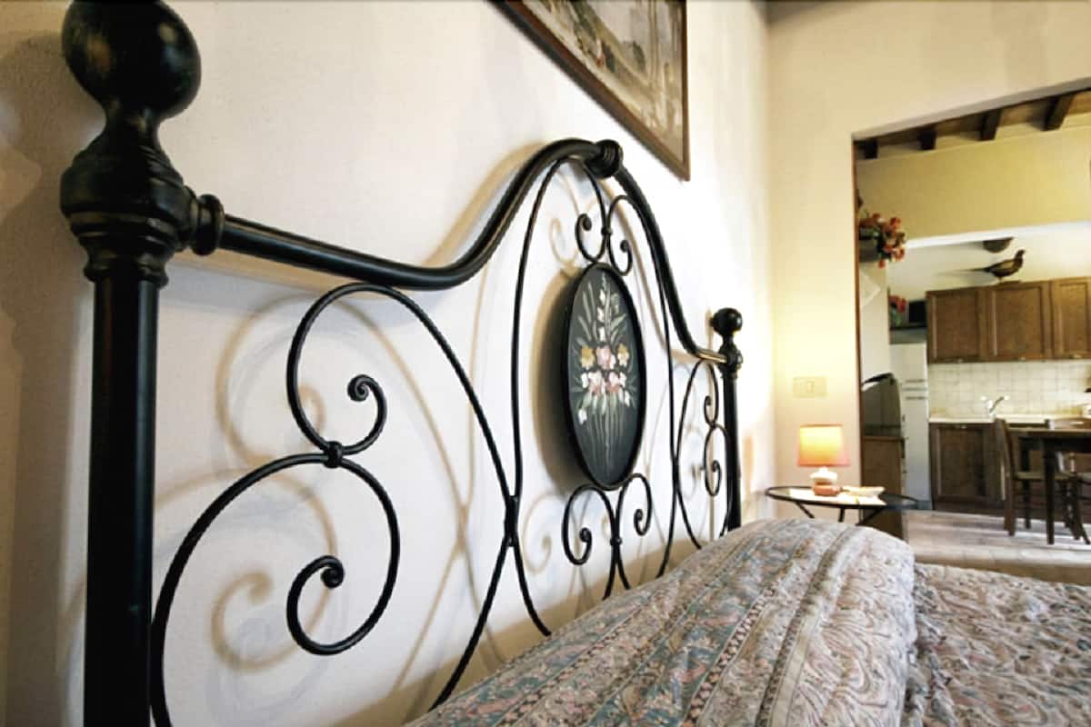 A bed with a patterned bedspread and a black metal headboard with a decorative mirror.