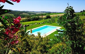 Una piscina rectangular rodeada de césped cuidado, con vistas claras a colinas onduladas al fondo.