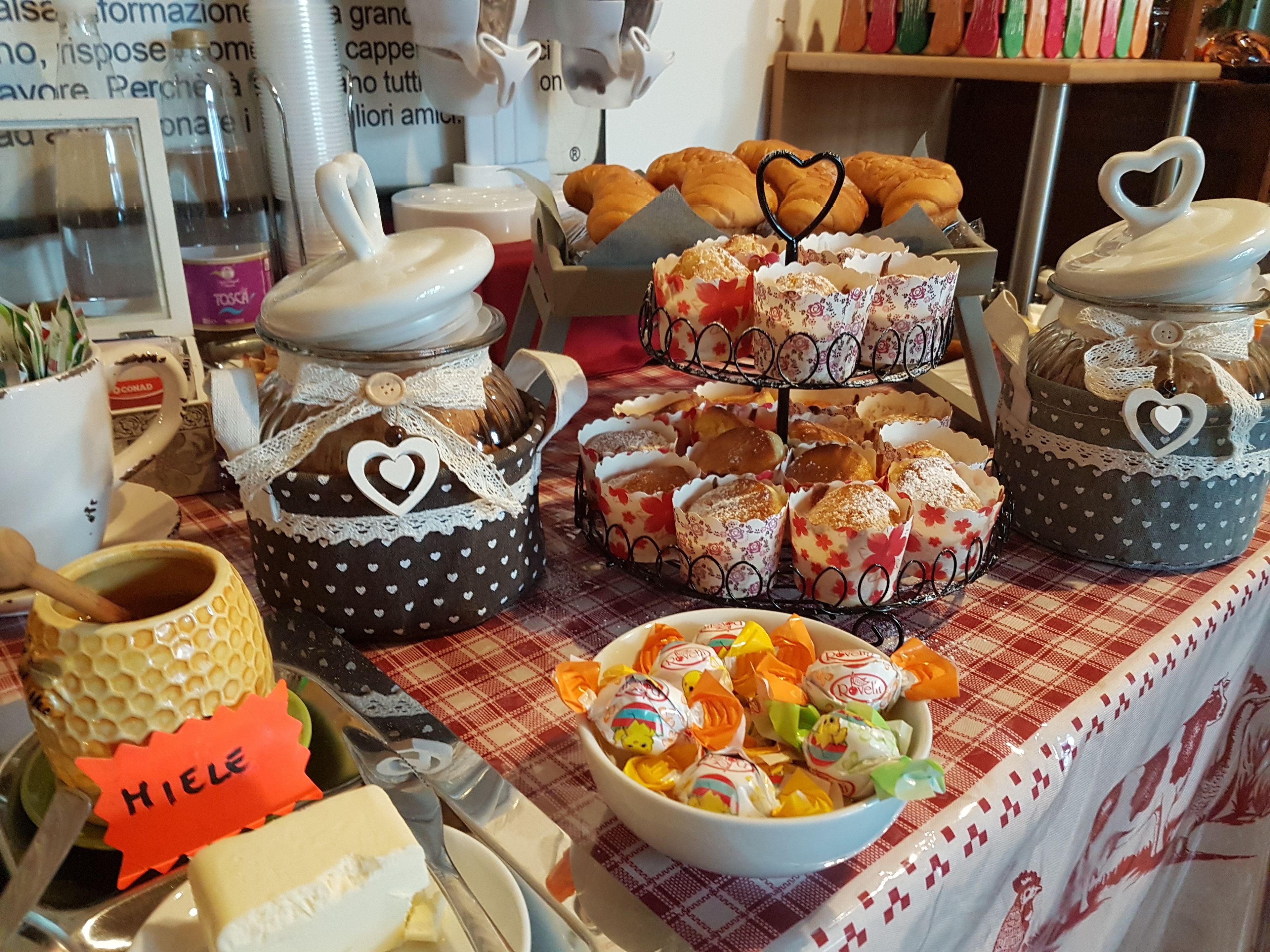 A table with jars of honey, a bowl of candies, and pastries.