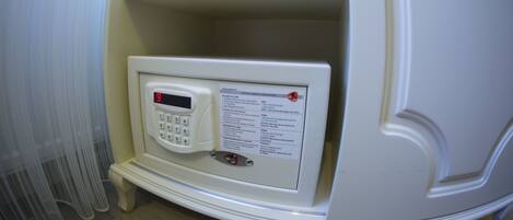 A room with a white wall, a small shelf with books, and a control panel with a digital display.