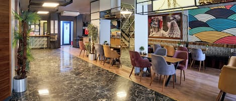 A modern interior with a marble floor, seating areas, a staircase, and a colorful mural.