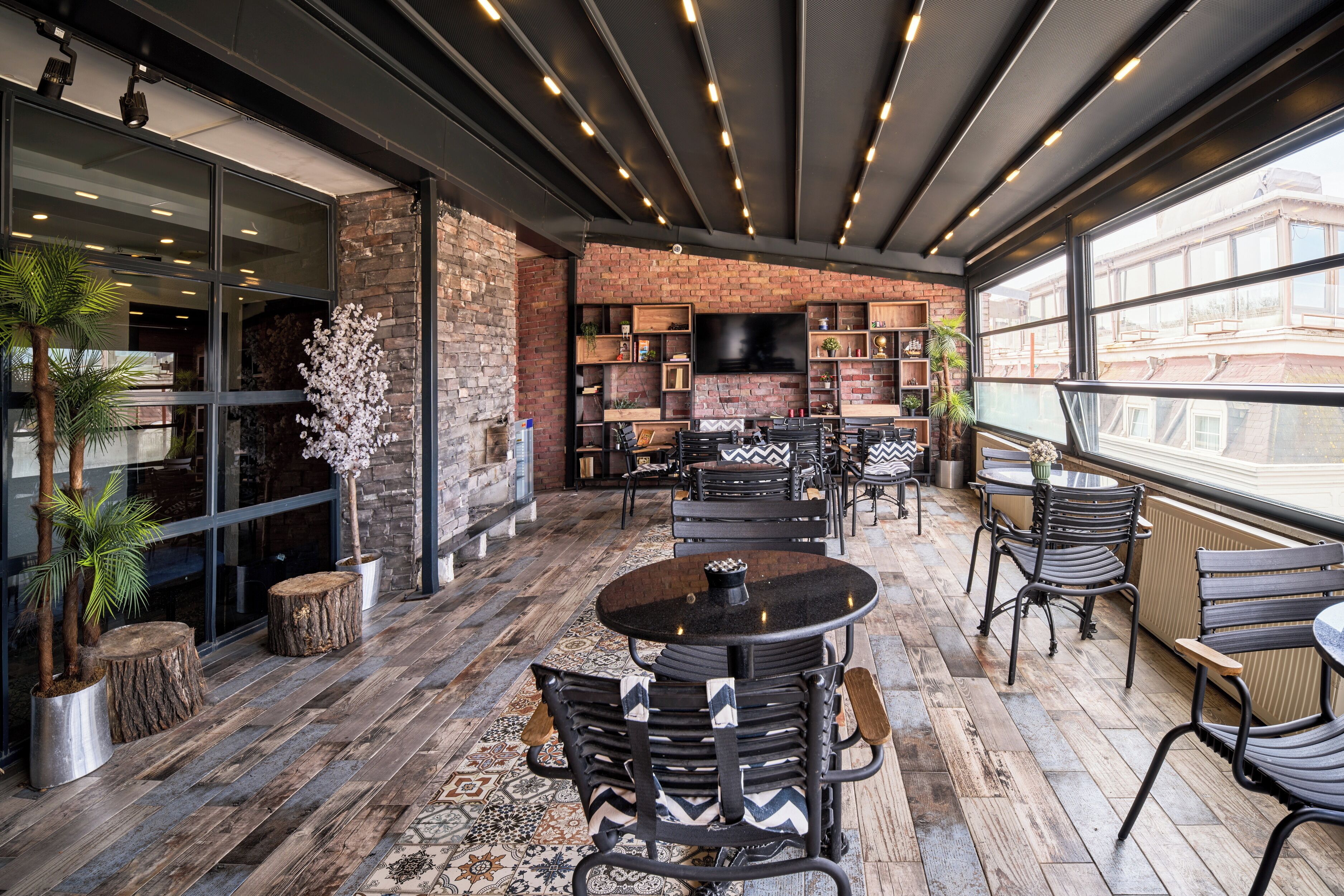 An indoor seating area with brick walls, a large TV screen, and a variety of seating options.
