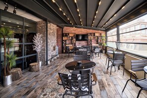 An indoor seating area with brick walls, a large TV screen, and a variety of seating options. - Sirkeci Ersu Hotel (Istanbul)