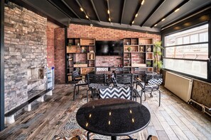A cozy indoor seating area with brick walls, a flat-screen TV, and a mix of wooden and metal furniture. - Sirkeci Ersu Hotel (Istanbul)