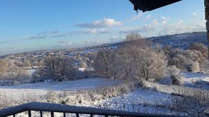 A view from a covered balcony overlooking a snowy landscape with trees and distant buildings. - B&B Gennargentu (Fonni)