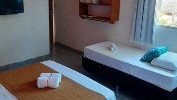 Une chambre d’hôtel avec deux lits, une télévision, une étagère en bois et une fenêtre avec des rideaux.