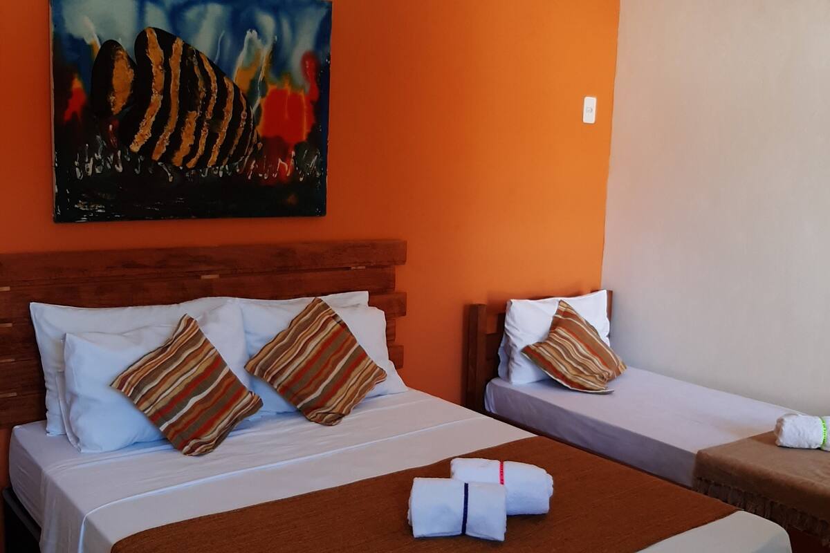 A hotel room with two beds, each with white linens and striped pillows. There is a painting on the wall above the beds.
