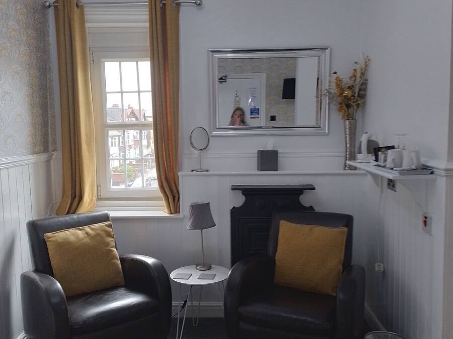 A small, well-lit room with two leather armchairs, a small table, a mirror, and a fireplace.