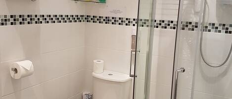 A modern bathroom with a glass-enclosed shower, a toilet, and a towel rack with neatly folded towels.