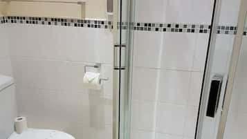 A bathroom with a toilet, a glass shower enclosure, and a towel.