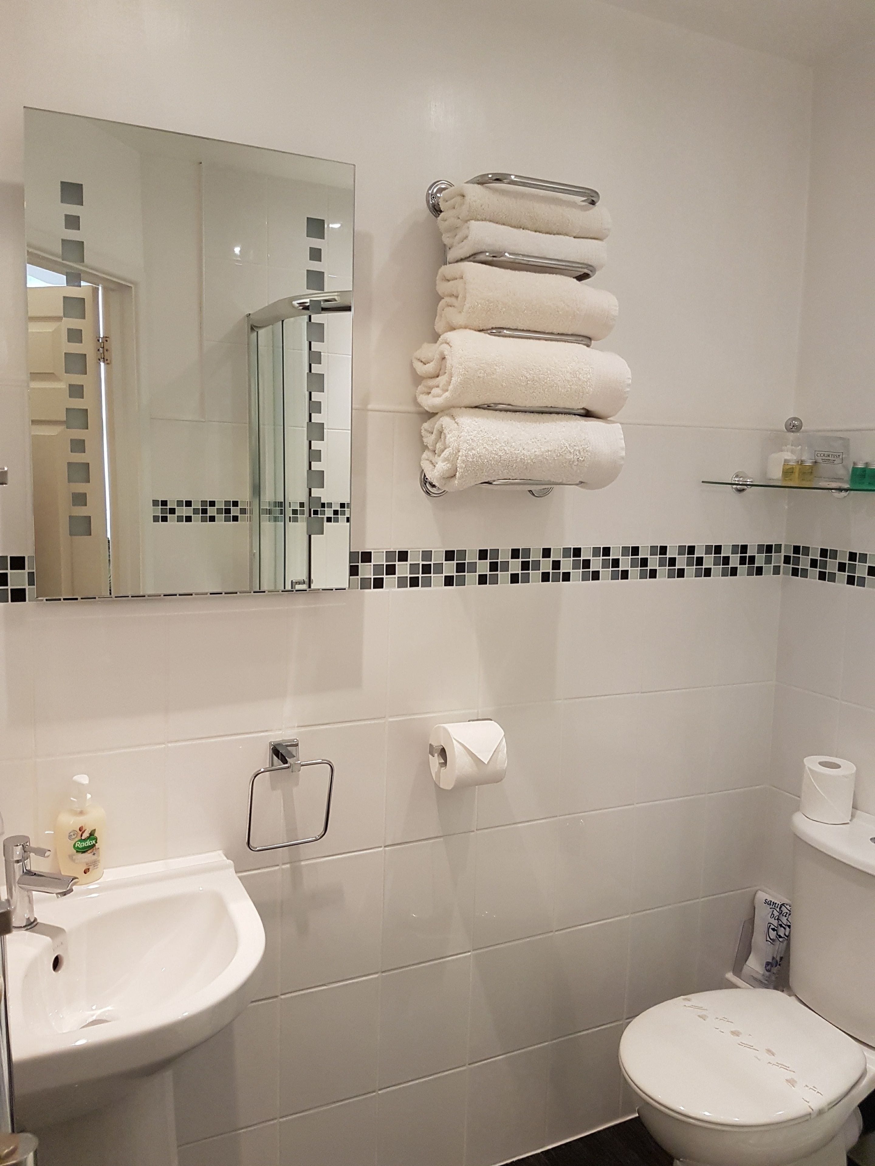 A bathroom with a sink, toilet, and a towel rack with folded towels.