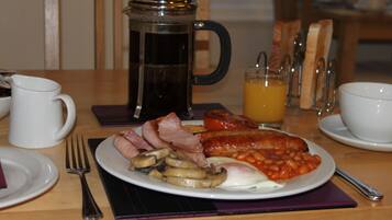 A breakfast plate with eggs, beans, mushrooms, and sausages.