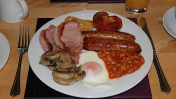 Un plato de comida para el desayuno con salchichas, huevos, champiñones y frijoles horneados.