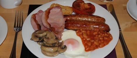 Un plato de comida para el desayuno con salchichas, huevos, champiñones y frijoles horneados.