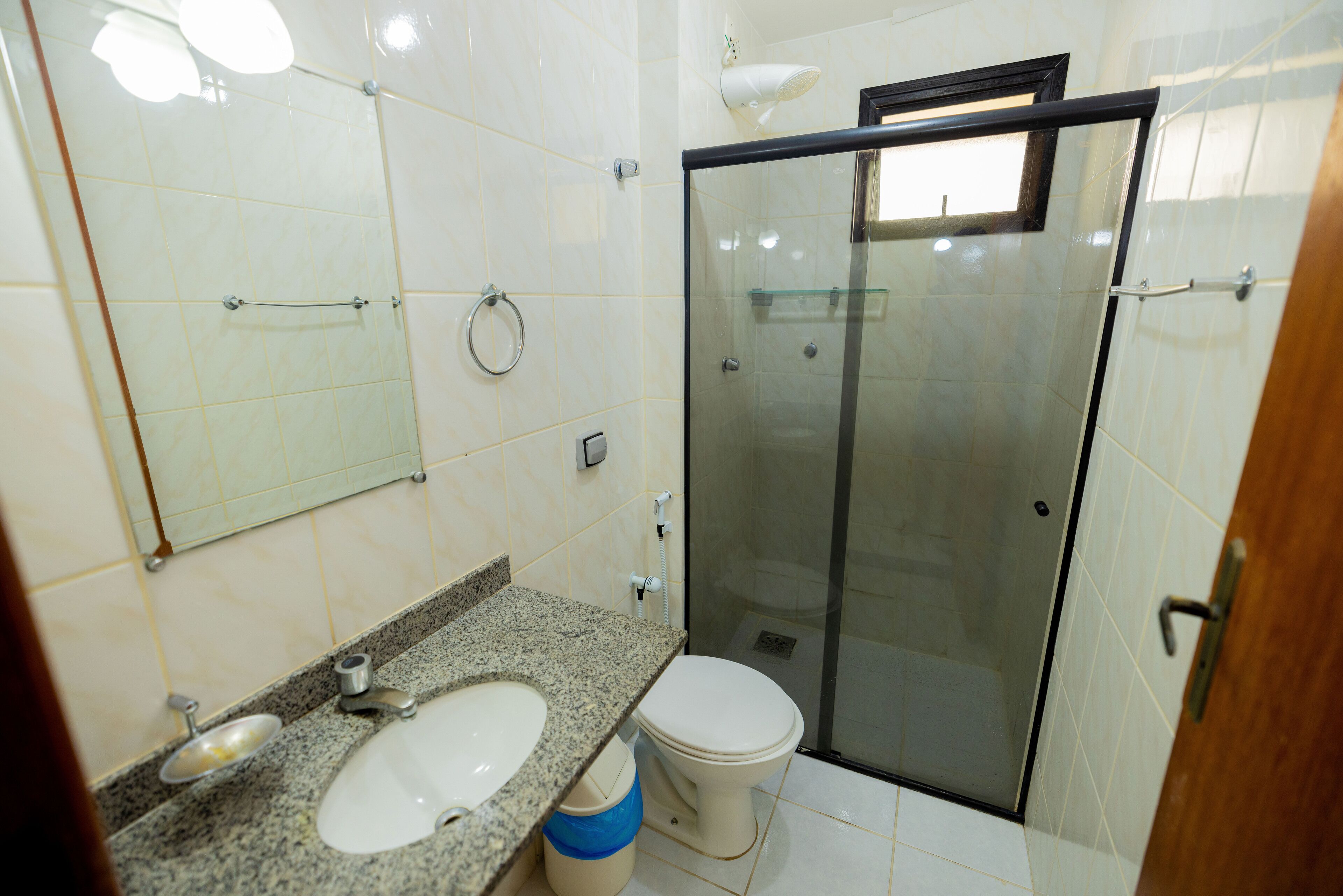 Ein Badezimmer mit Marmorwaschtisch, Toilette und einer Duschkabine.