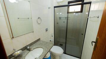 Ein Badezimmer mit Marmorwaschtisch, Toilette und einer Duschkabine.