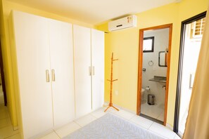 A room with a large wardrobe, a standing lamp, and a view into the bathroom.