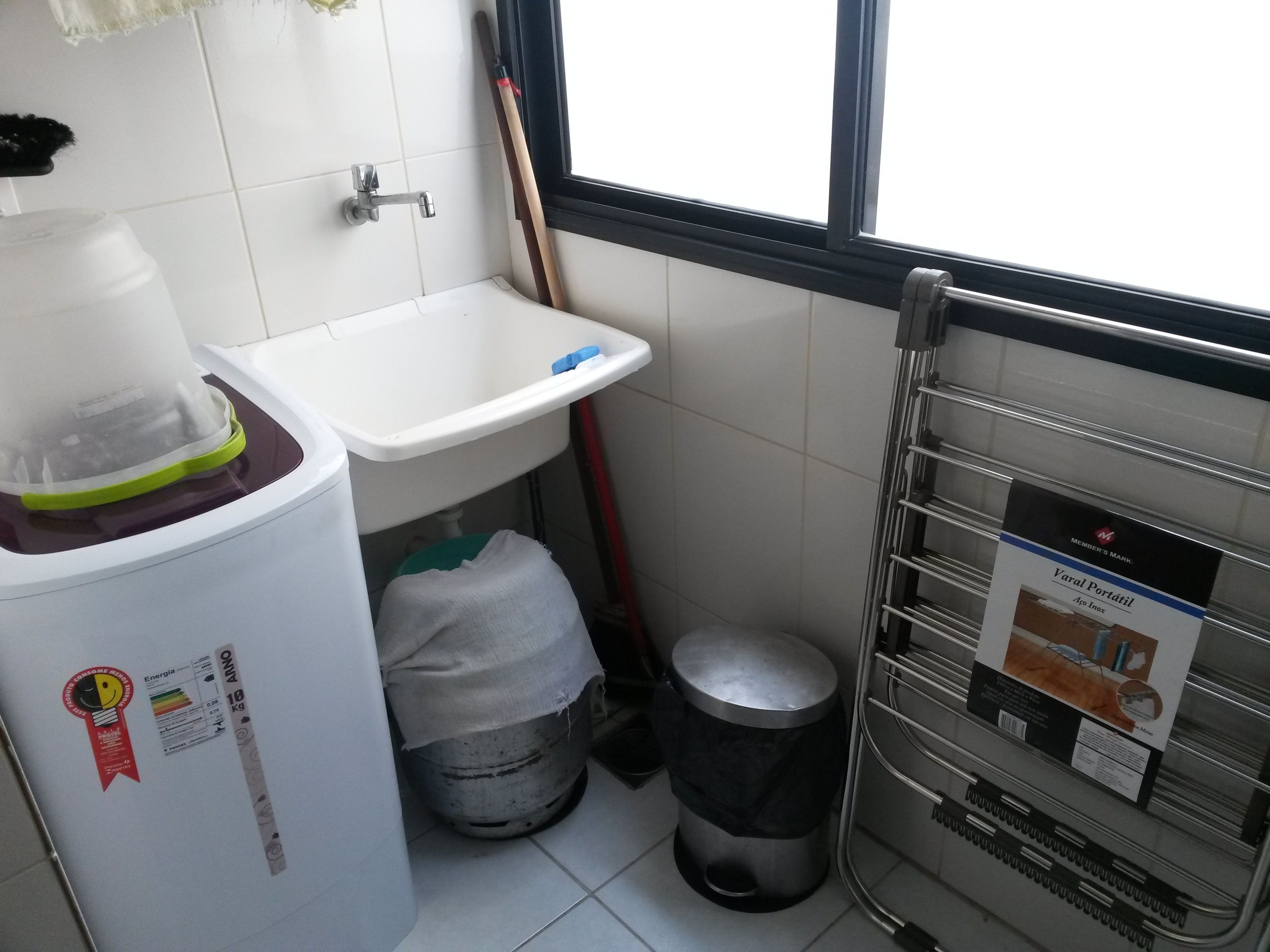 A small bathroom with a white sink, a trash bin, a storage unit, and a window.