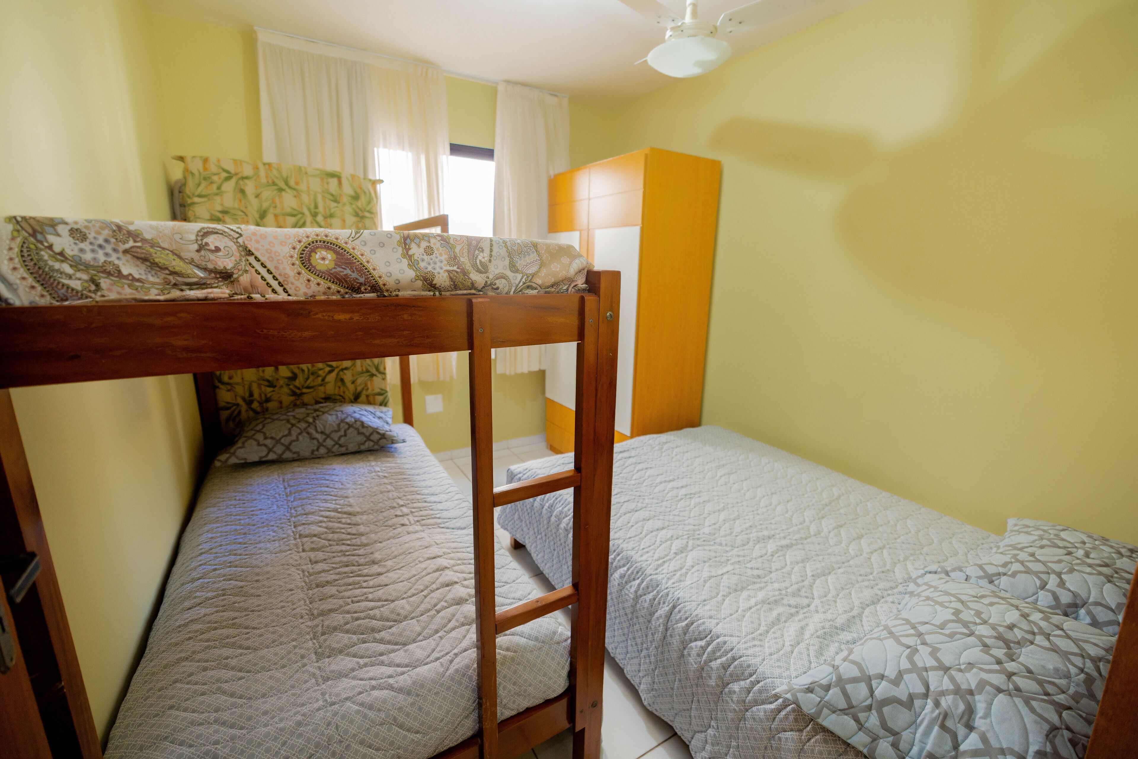 Una camera del dormitorio con letti a castello, una scala in legno e un letto singolo.
