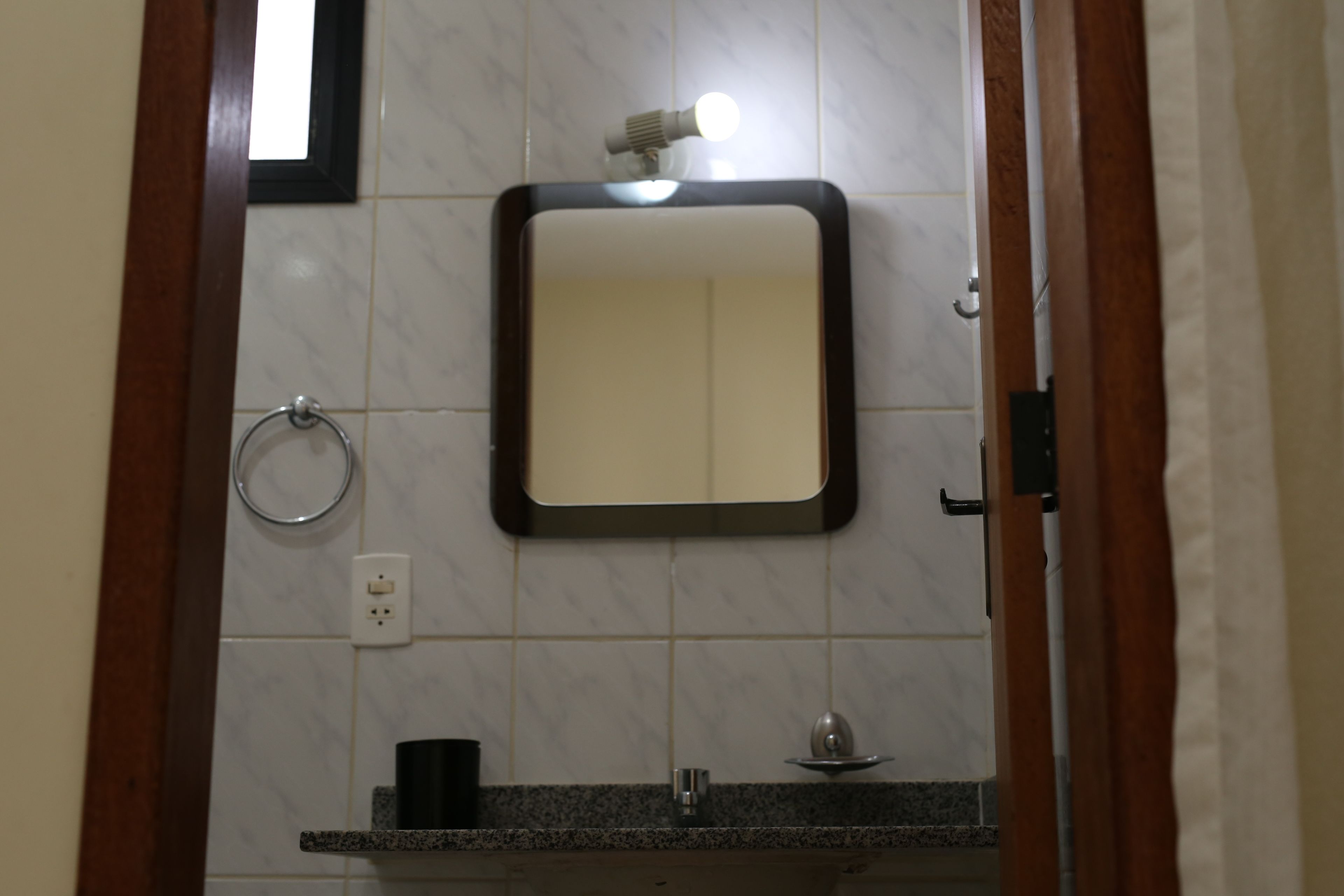 Un baño con espejo, lavamanos y dispensador de papel higiénico.