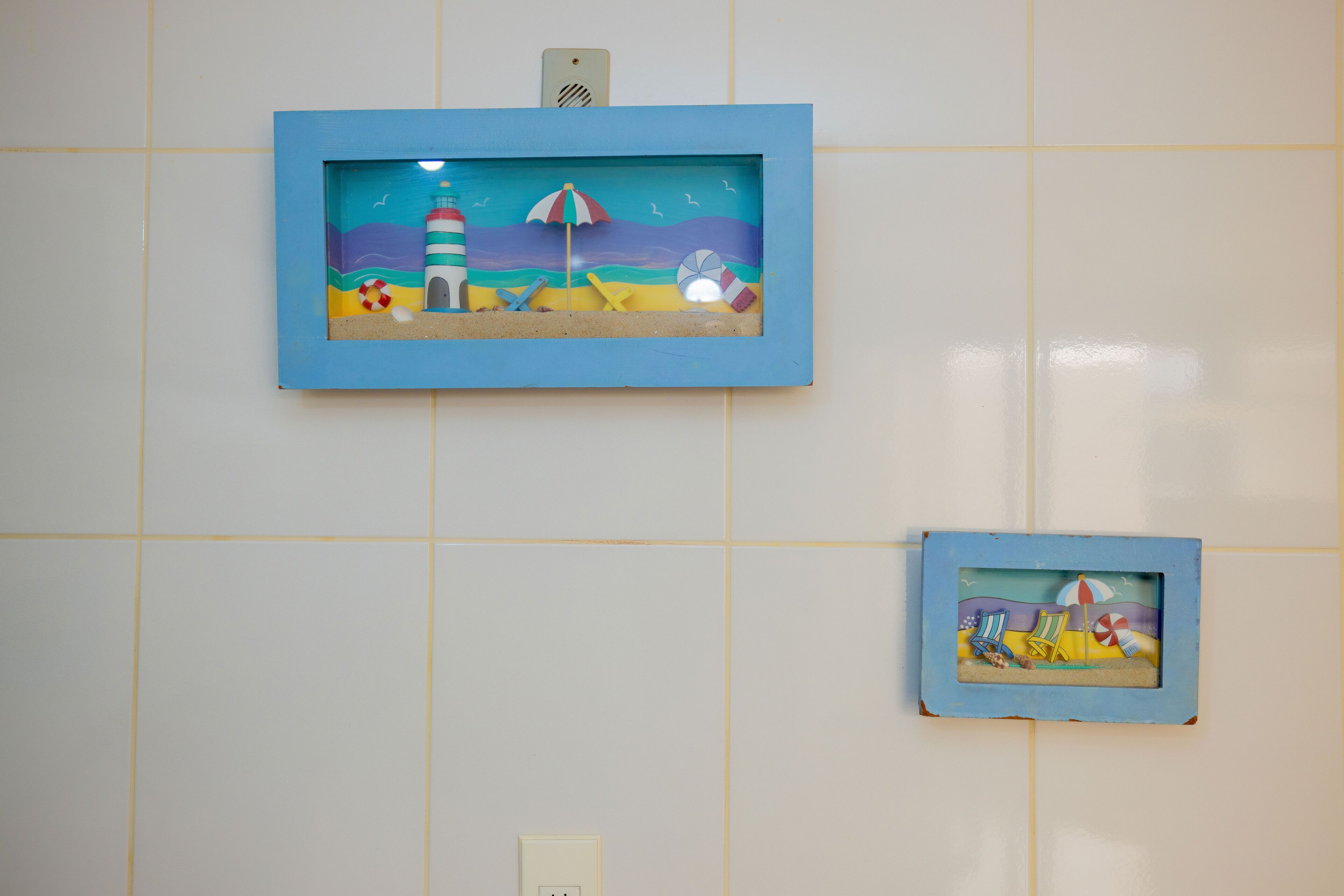 Two framed beach scenes on a tiled wall.