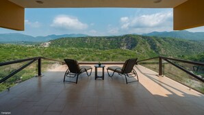 Un balcón con dos sillas y una mesa, con vistas a un paisaje montañoso.