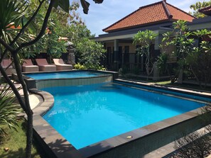 Una piscina con sillas de descanso y un deck de azulejos.