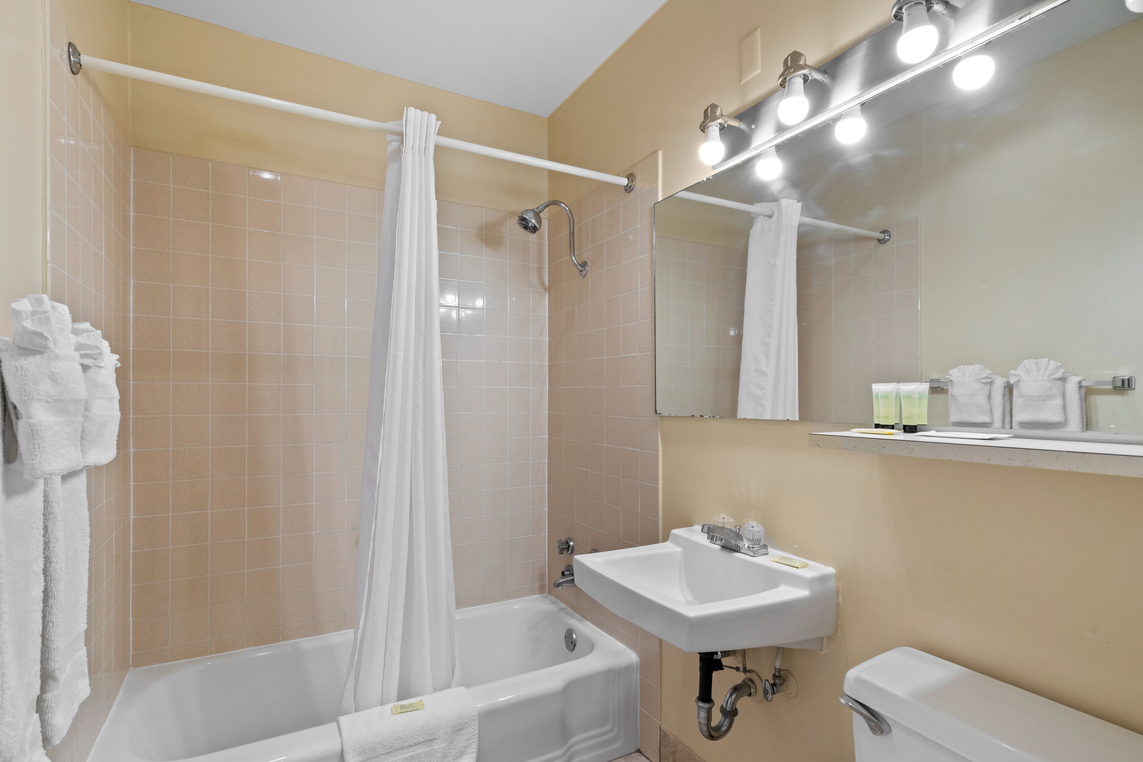 A bathroom with a bathtub, a sink, a mirror, and a shower curtain.