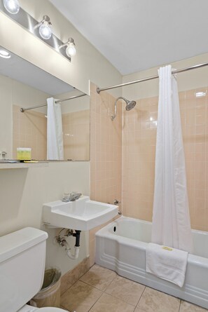 Une salle de bain équipée de toilettes, d’un lavabo, d’une baignoire et d’un rideau de douche.