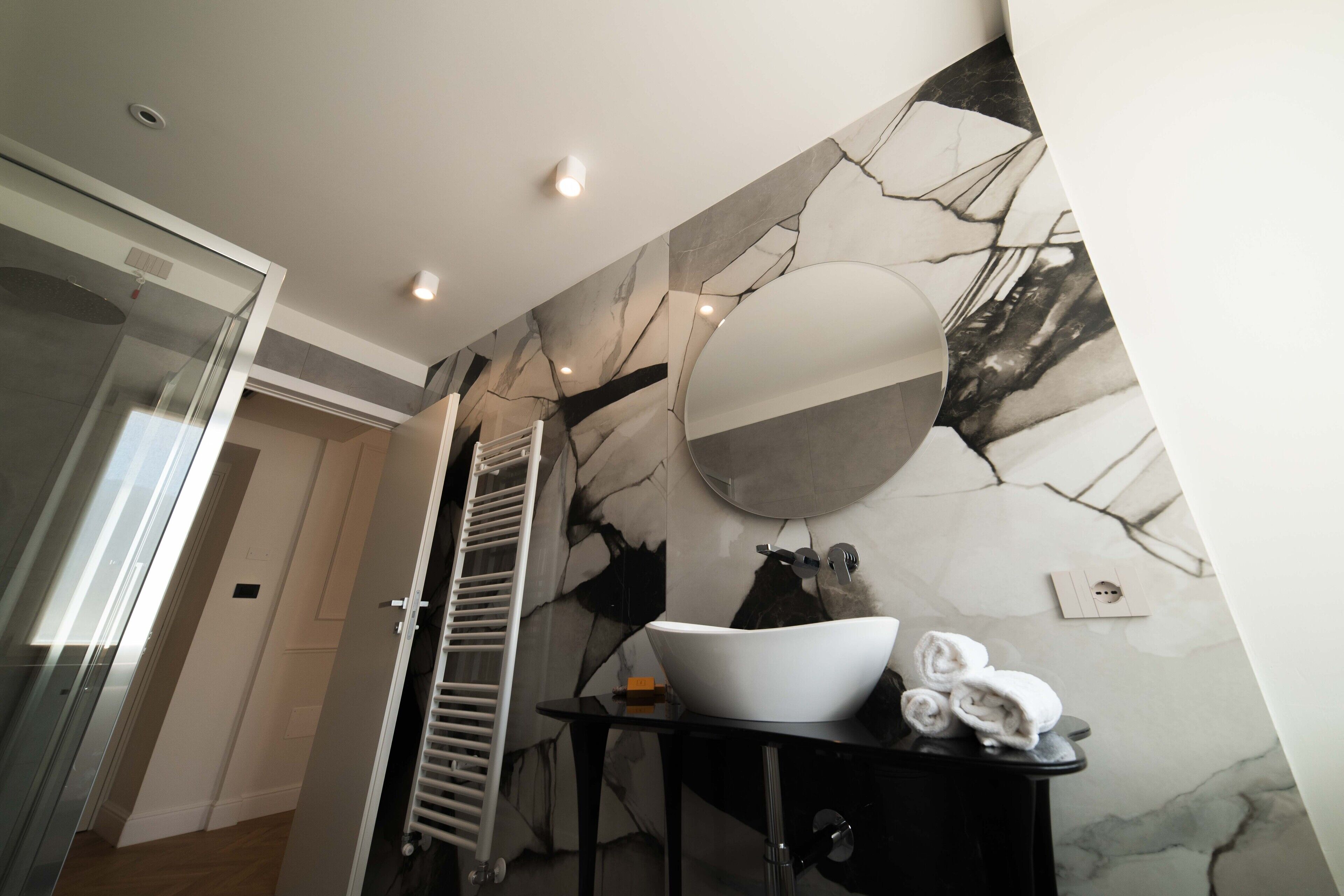 Un baño moderno con un espejo grande, un lavabo blanco y un perchero para toallas.