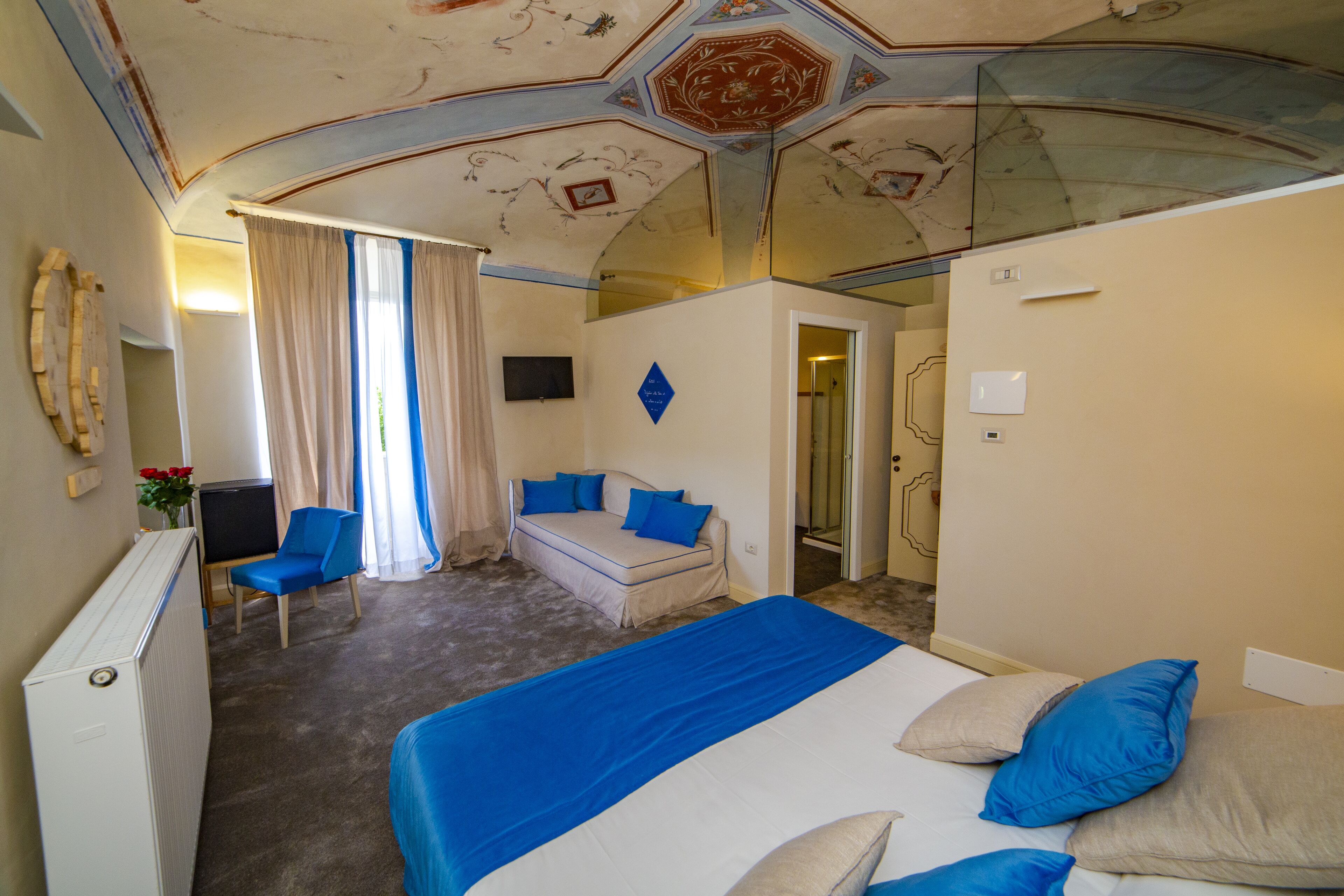 Una habitación de hotel con una cama grande, un sofá, una silla y una televisión.