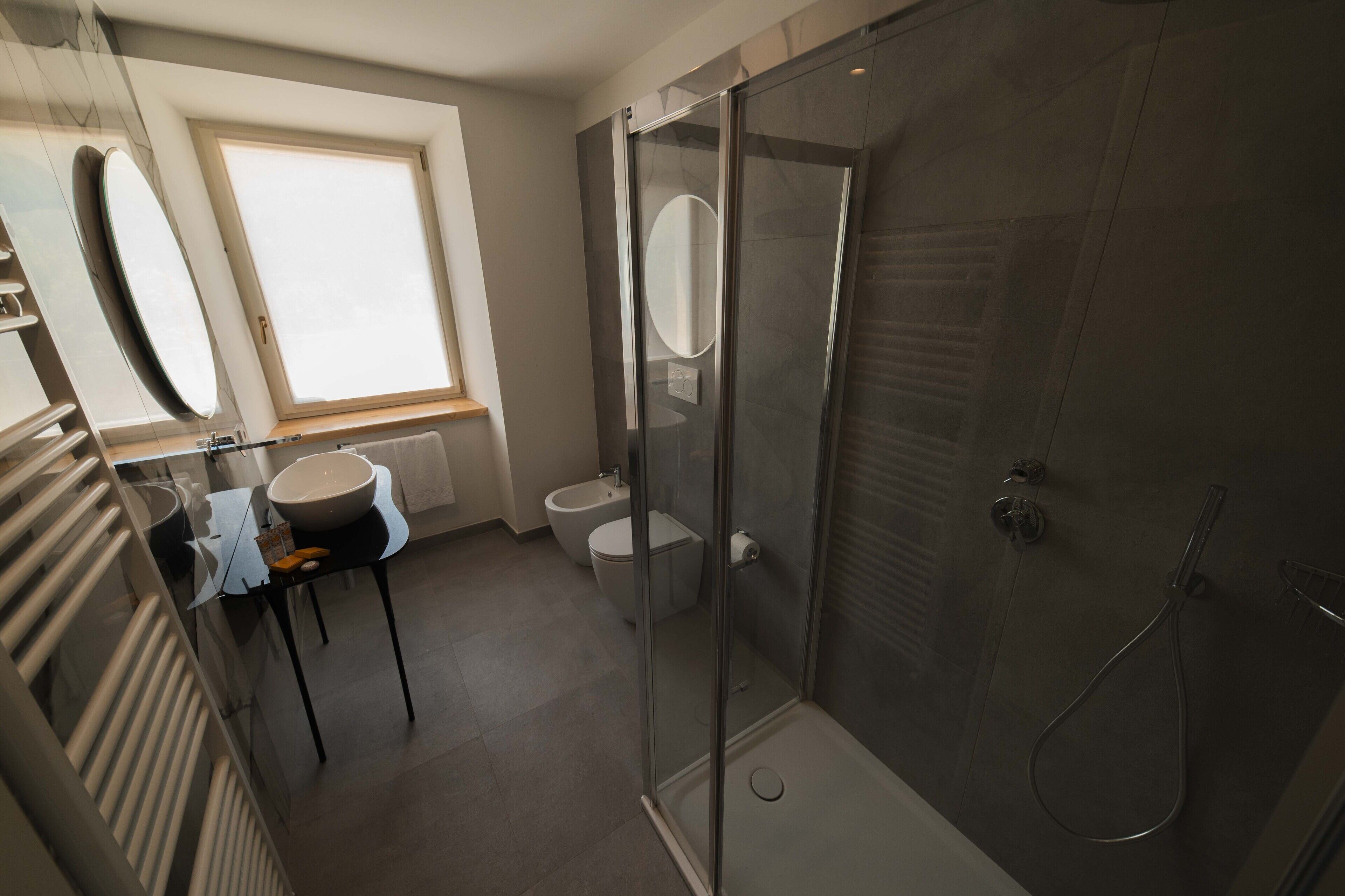 Une salle de bain moderne avec une douche à parois de verre, un lavabo avec un miroir et des toilettes.