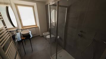 Une salle de bain moderne avec une douche à parois de verre, un lavabo avec un miroir et des toilettes.
