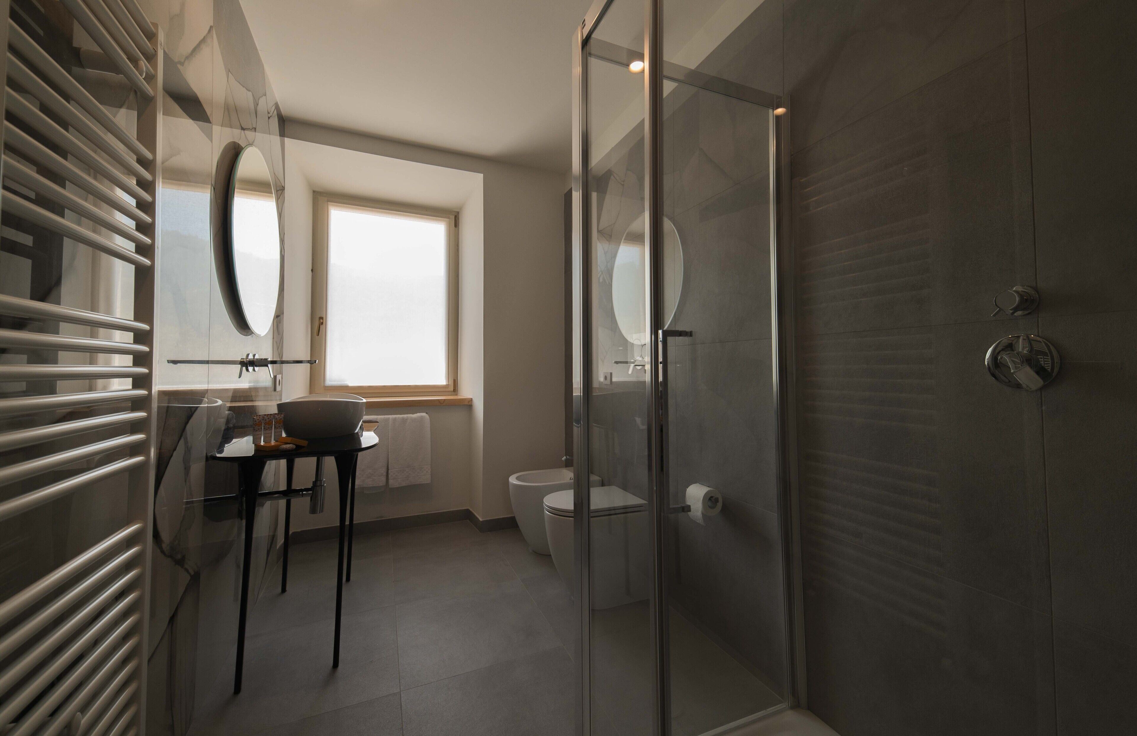 A modern bathroom with a glass shower enclosure, a toilet, and a sink with a mirror.