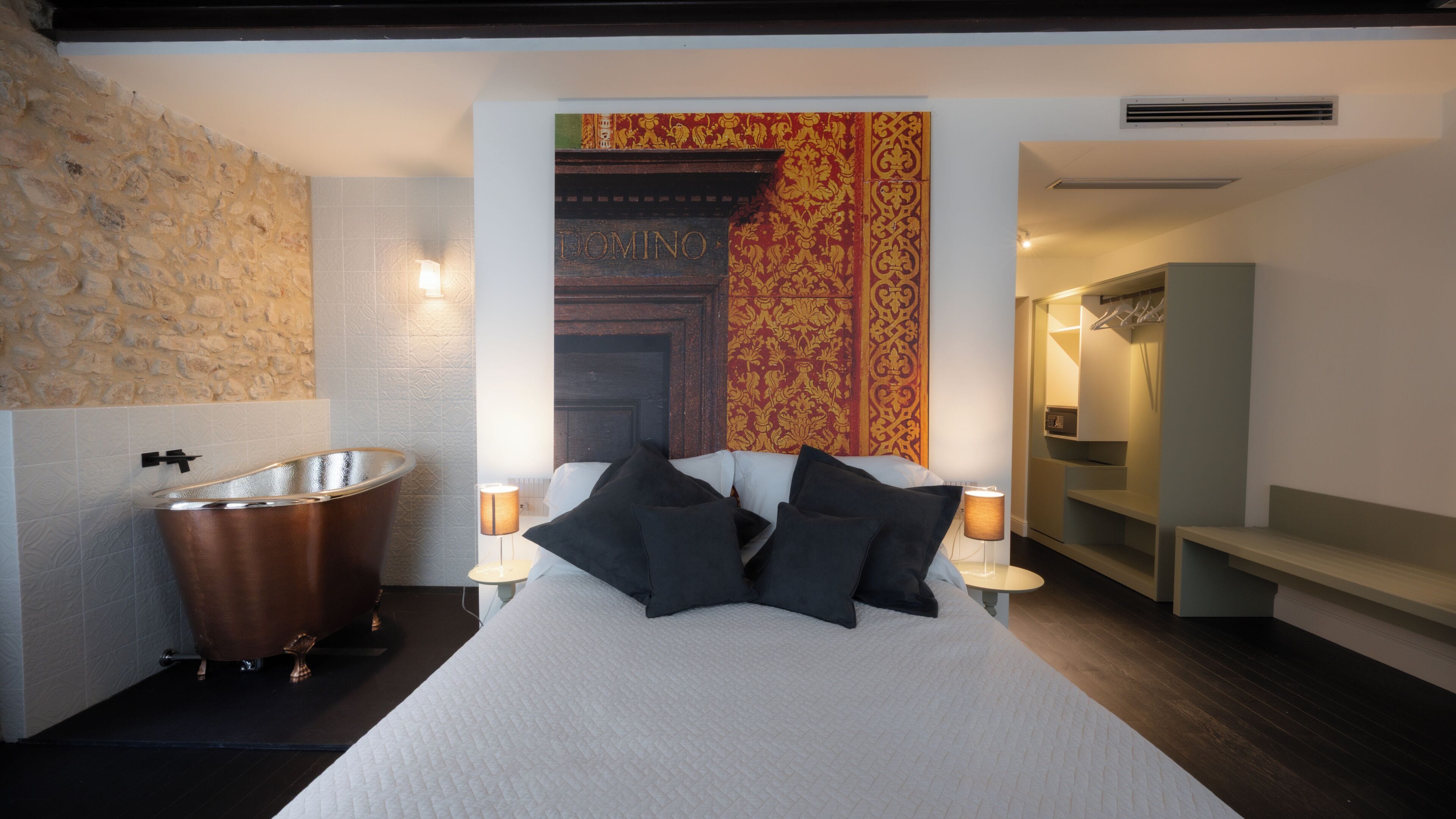 A bedroom with a large bed, a bathtub, and a wardrobe.