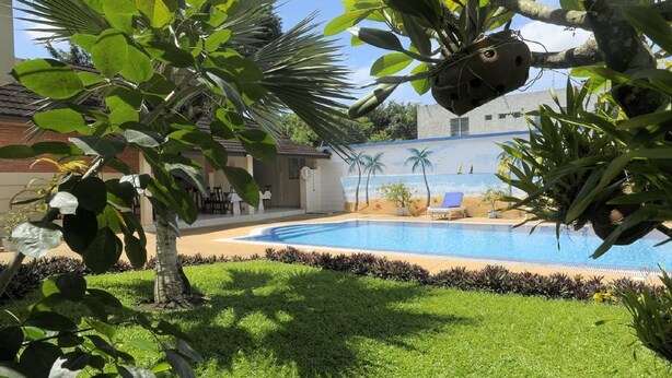 Piscina cercada por vegetação exuberante e um mural retratando uma cena de praia.