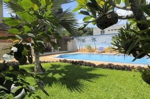 A swimming pool surrounded by lush greenery and a mural depicting a beach scene.