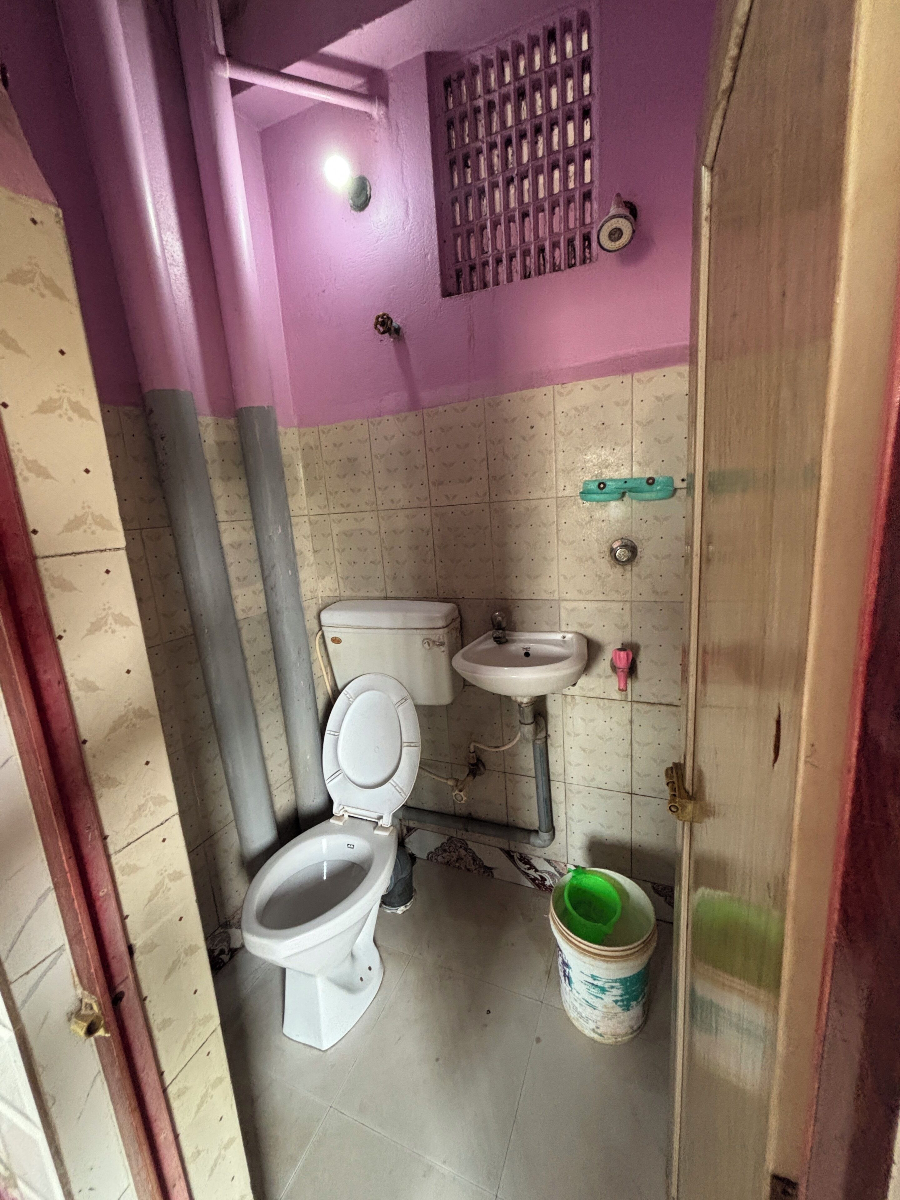 A small bathroom with a toilet, sink, and a bucket.