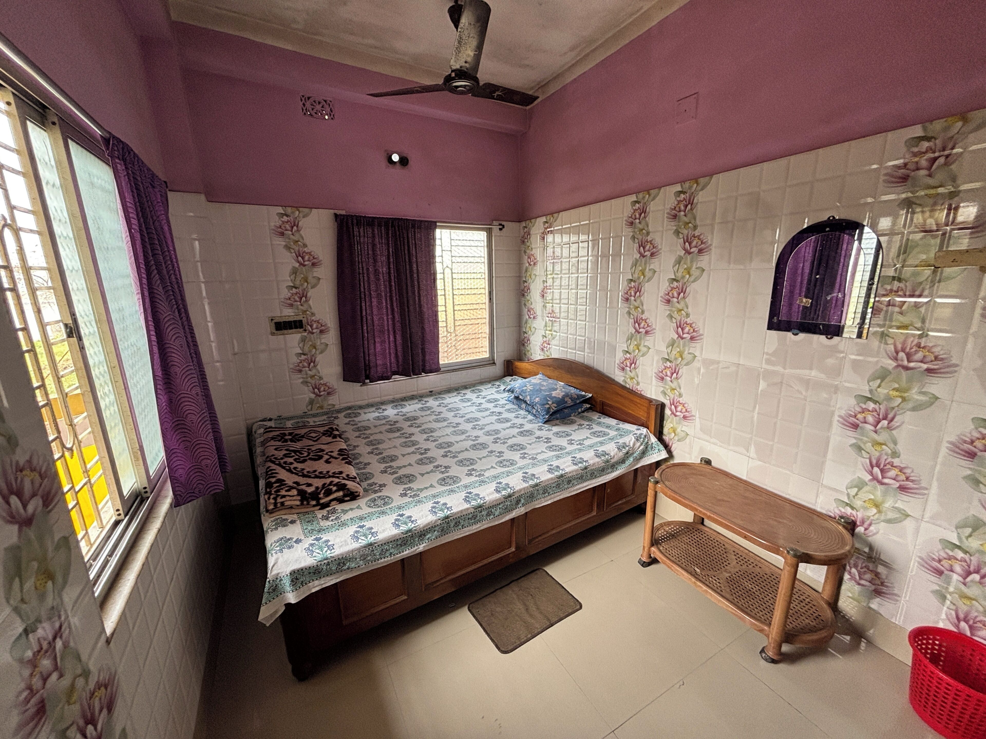 A bedroom with a bed, a wooden bench, a red basket, and a ceiling fan.