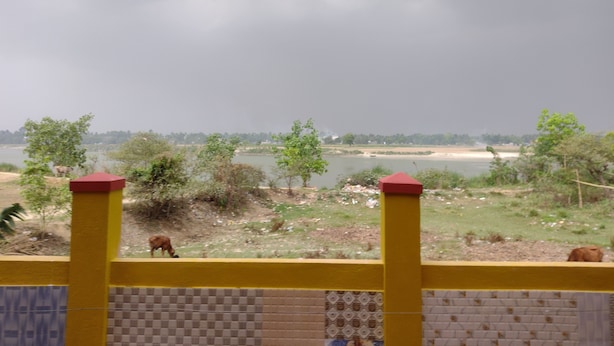 A view of a river with trees and a distant cityscape under a cloudy sky. - Jagannath Guest House (Krishnanagar)