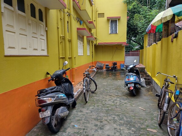 A narrow alley with yellow and orange walls, parked scooters, and a bicycle. - Jagannath Guest House (Krishnanagar)